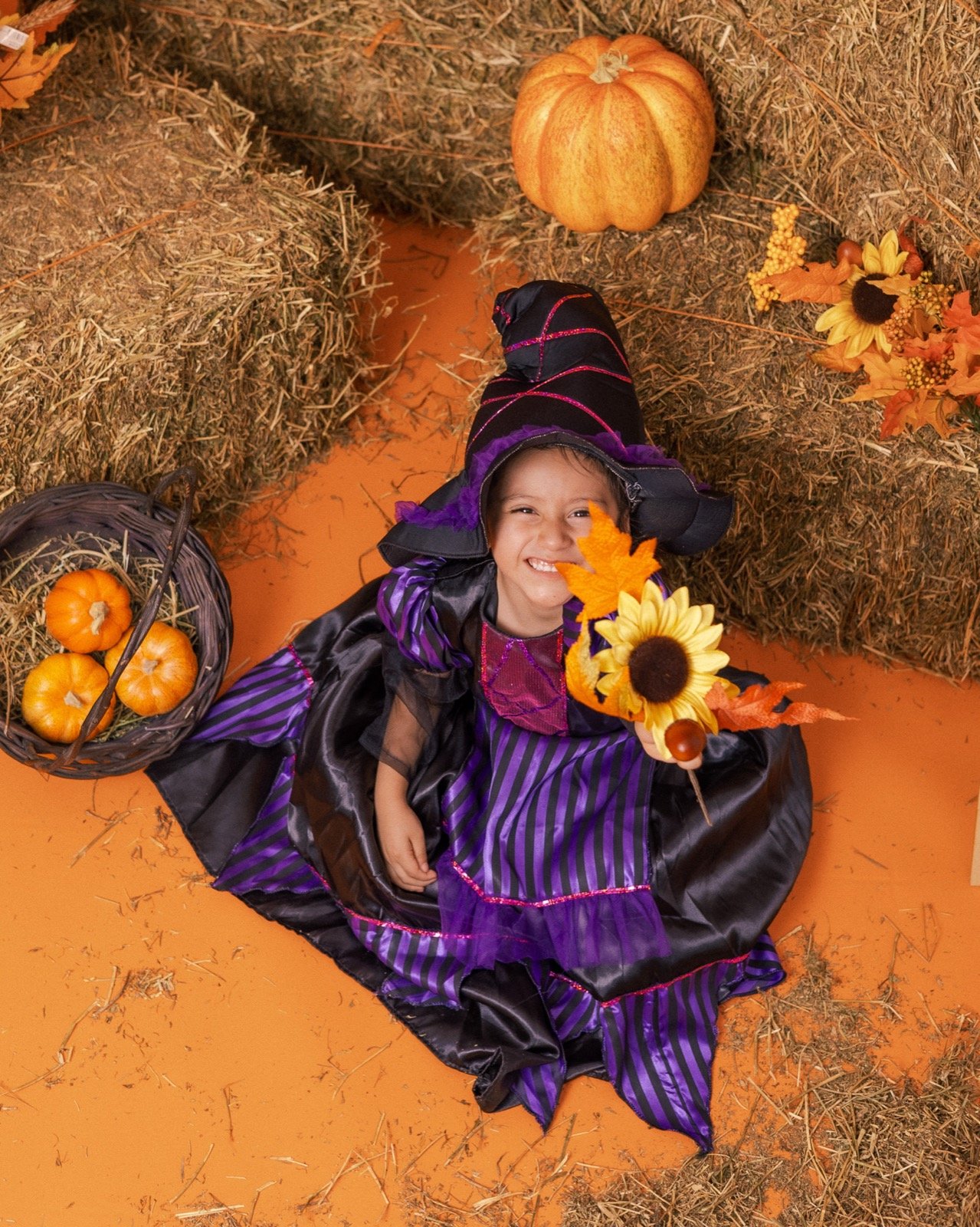 Niña disfrazada de bruja sonriendo en el set de otoño